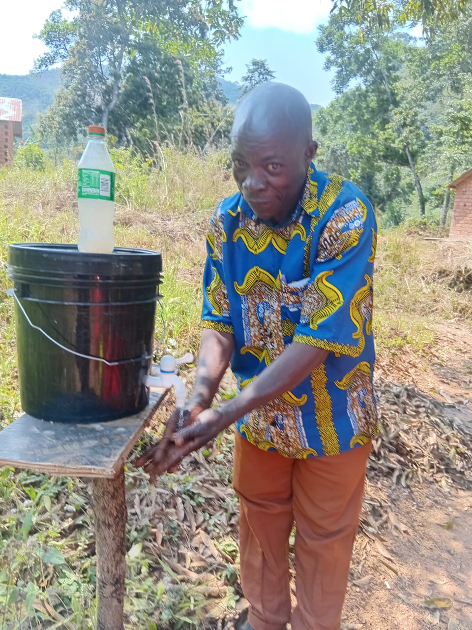 Community member washing hands at a bucket handwashing station
